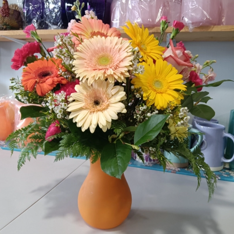 Vibrant flower bouquet in orange vase.