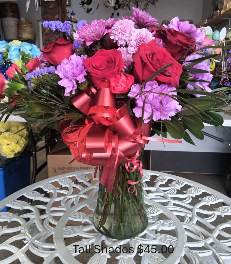 Flower bouquet with red ribbon in vase.